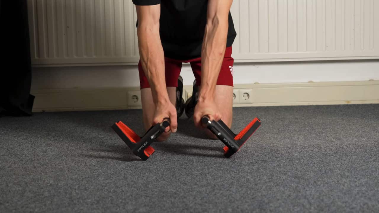 Man in red shorts showcasing the penchant for the Jayflex CrossGrips to tip over while using them as Push-Ups Bars.