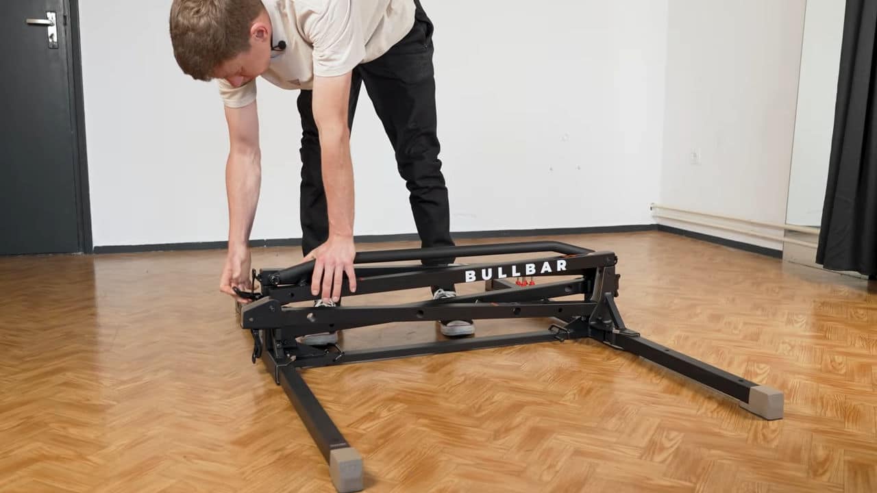 Man preparing the folded bullbar 2.0 foldable pull-up bar for extension and final setup.