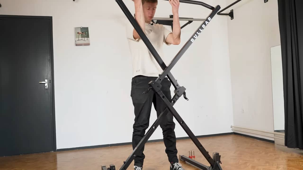 Man raising up the bullbar 2.0 foldable pull-up bar, extending like a harmonica to its full height.