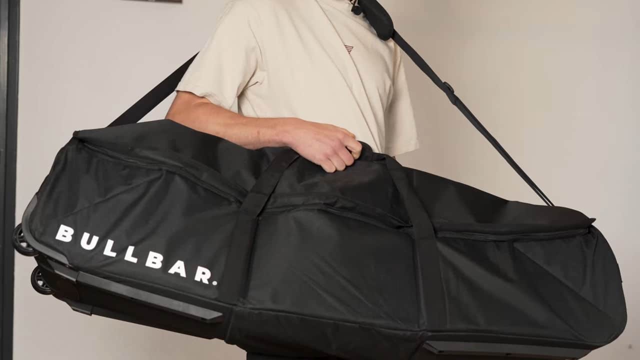 Man carrying the carry bag for the bullbar 2.0 foldable pull-up bar by the shoulder strap.