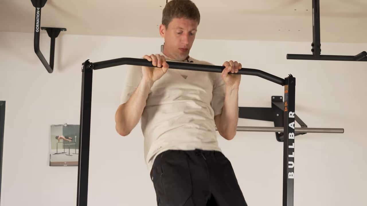 Man in beige shirt performing a normal pull-up on the bullbar 2.0 foldable pull-up bar.