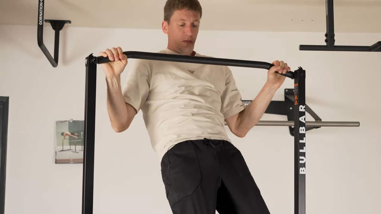 Man in beige shirt performing semi wide pull-ups on the bullbar 2.0 foldable pull-up bar.
