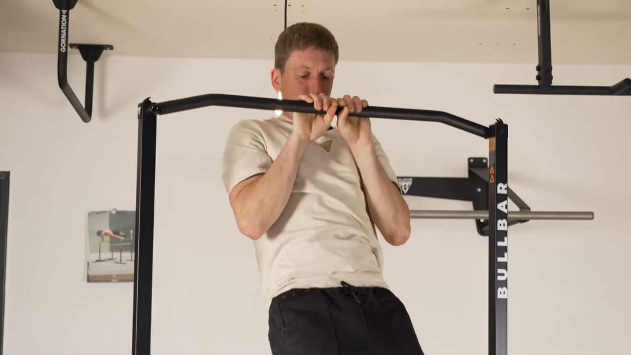 Man in beige shirt performing narrow grip pull-ups on the bullbar 2.0 foldable pull-up bar.
