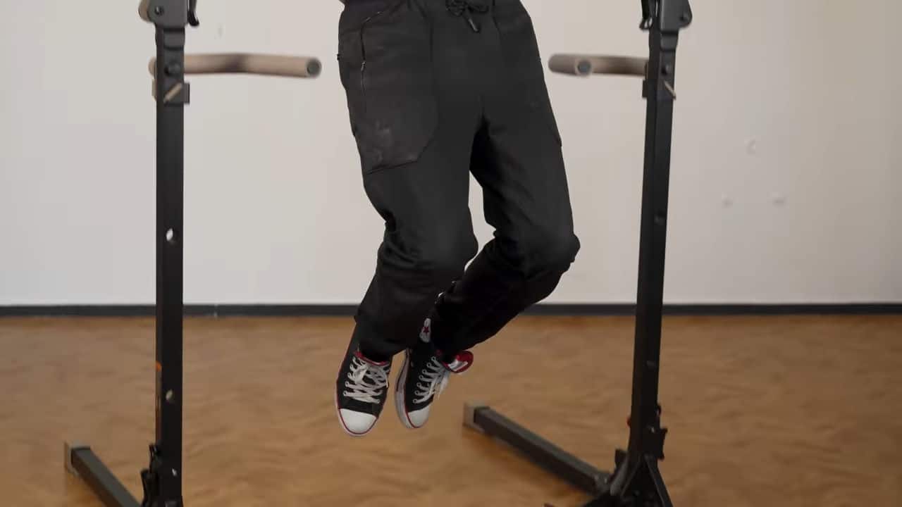 Man wearing a black cargo pants showing he has to bend his knees to do pull-ups on the bullbar 2.0 foldable pull-up bar.