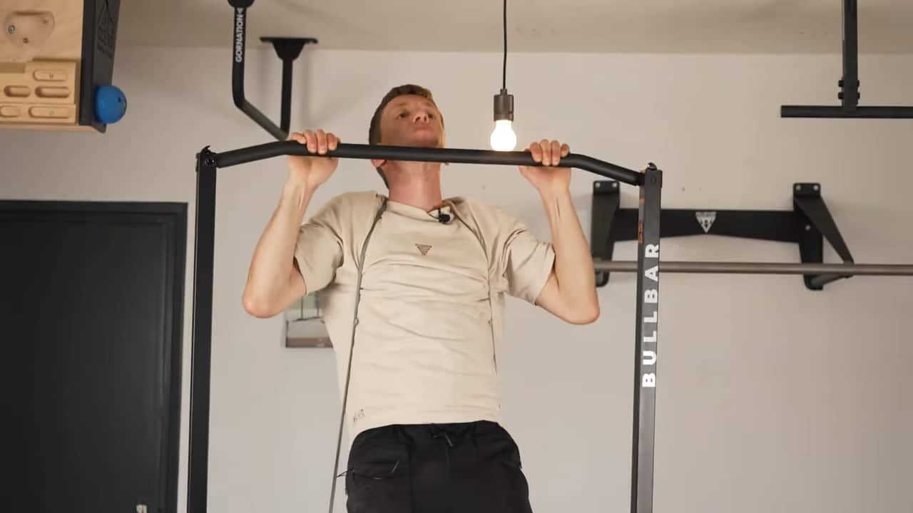 man wearing a resistance band around his shoulders doing pull-ups on the bullbar 2.0 foldable pull-up bar.