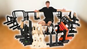 Man sitting amidst many samples of Calisthenics Parallettes and looking questioningly at the viewer.