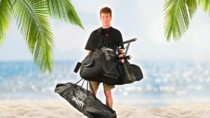 Man on a beach with a lot of different portable Pull-Up Bars around his neck and in his hands.