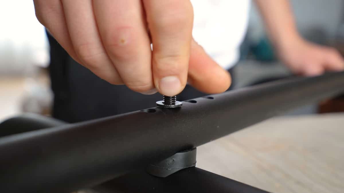 Close up of the Pullup & Dip Doorway Dip Bar assembly, a man fitting a nut into a hole.