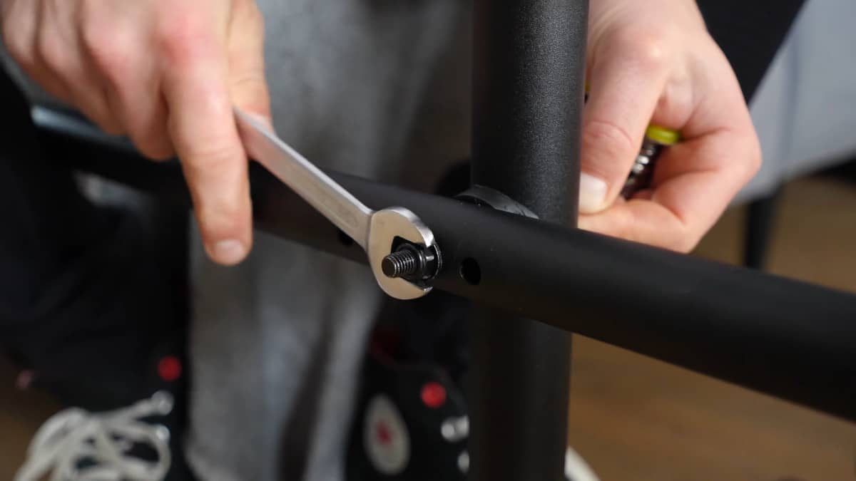 Close up of the Pullup & Dip Doorway Dip Bar assembly, a man tightening a nut with a spanner.