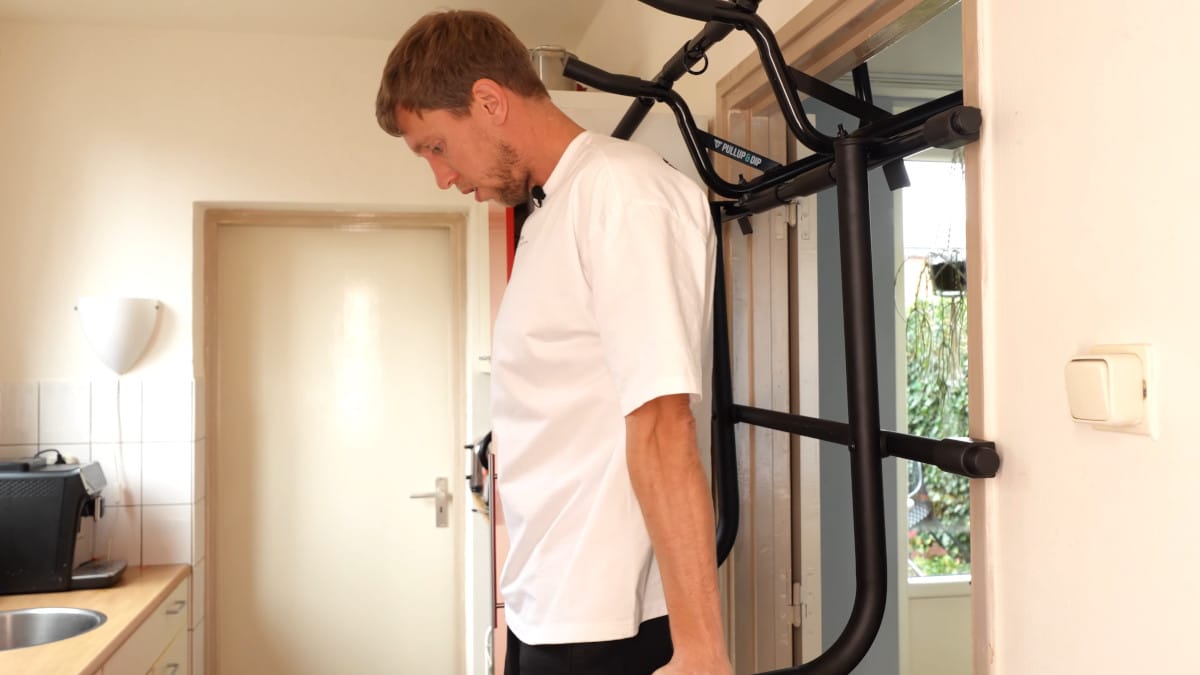 Man in white shirt performing dips on the Pullup & Dip Doorway Dip Bar.