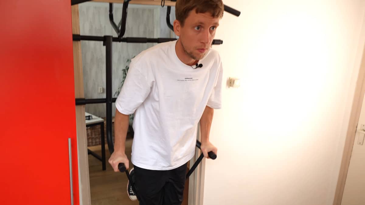Man in white shirt performing resistance band assisting dips on the Pullup & Dip Doorway Dip Bar.
