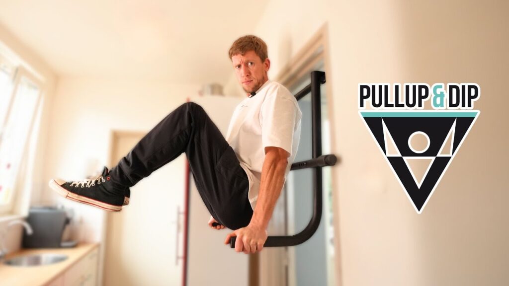 Man in white shirt looking suspiciously at the camera while performing an L-sit on the pullup & dip doorway dip bar.