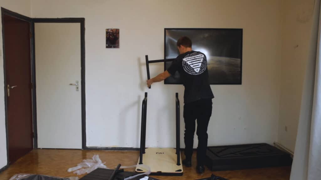 A man in black attire assembling the many different parts of the Fit Home Gym.