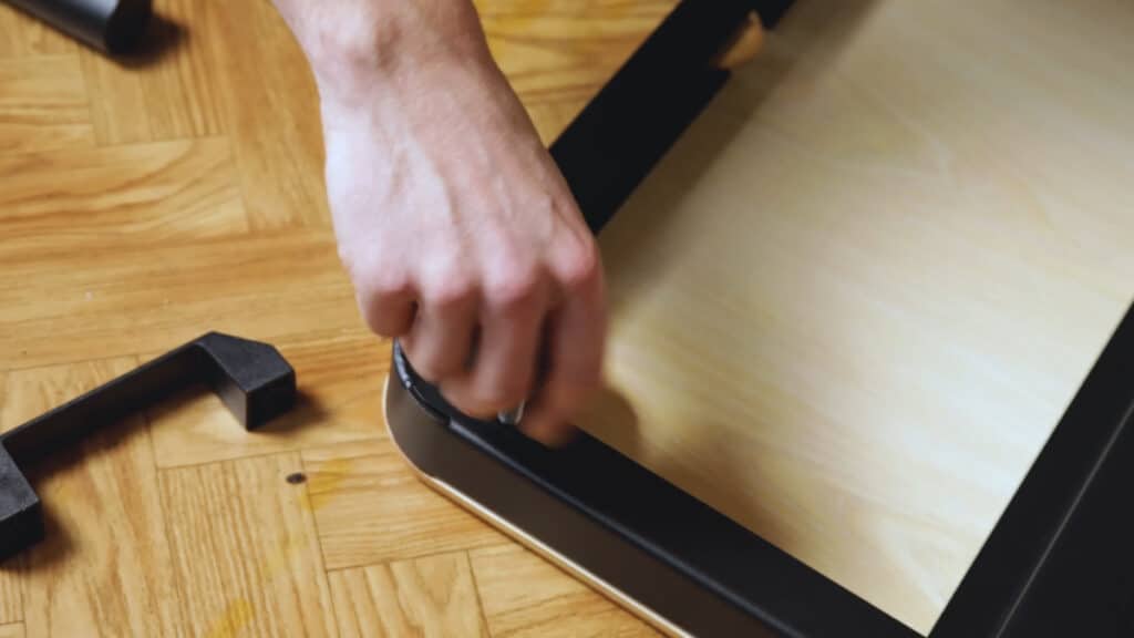 Close up of the assembly of the Fit Home Gym, a man is screwing in the feet on the baseplate.