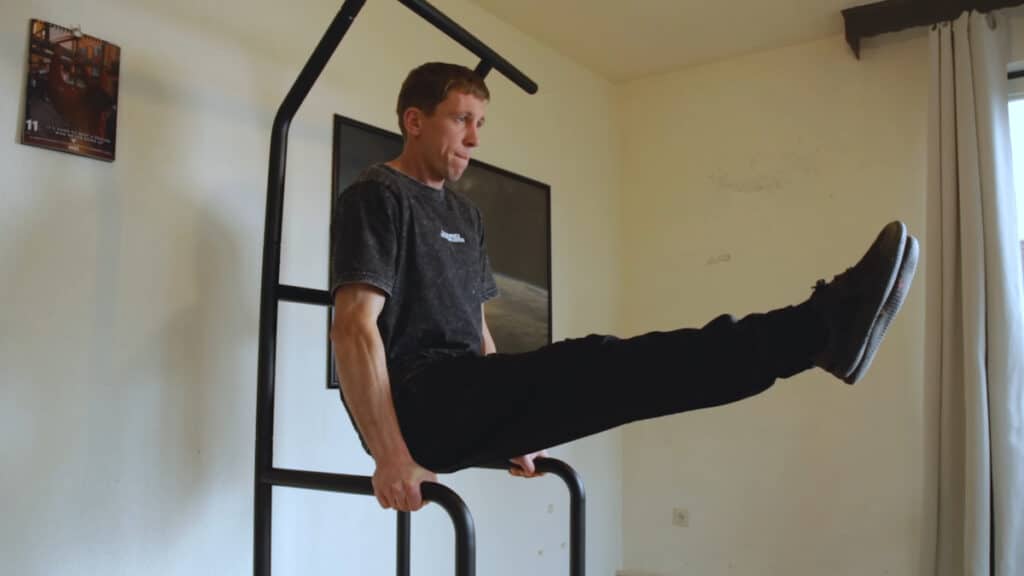 Man in black pants doing an L-sit exercise on the Fit Home Gym.