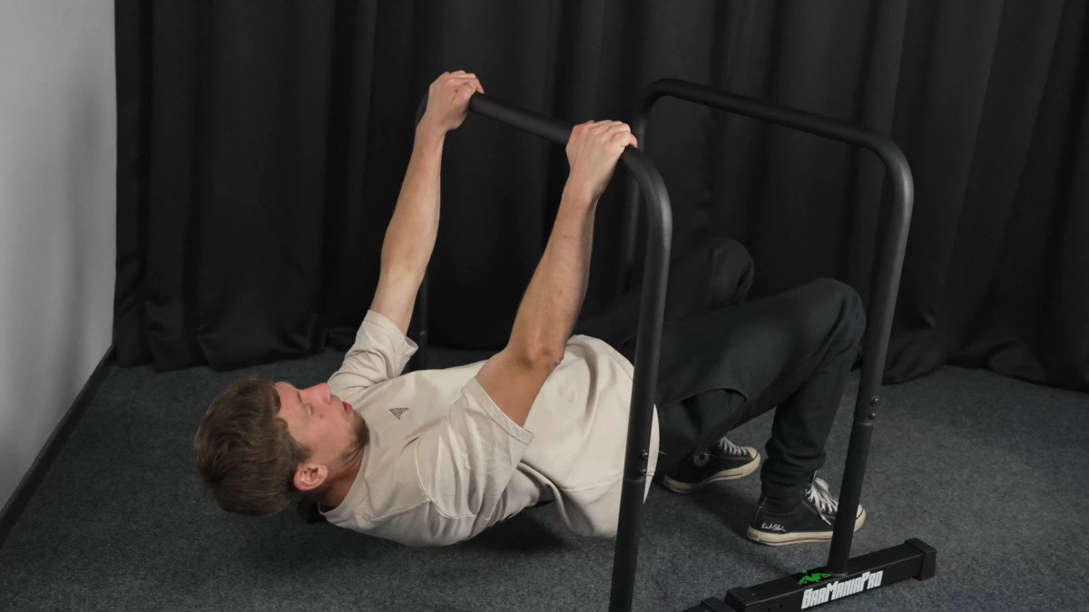 Man in white shirt performing rows on the barmania pro classic dip bars.