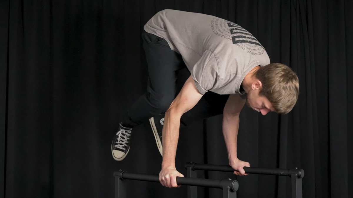 Man in white shirt performing a handstand on the barmania pro neo dip bars.