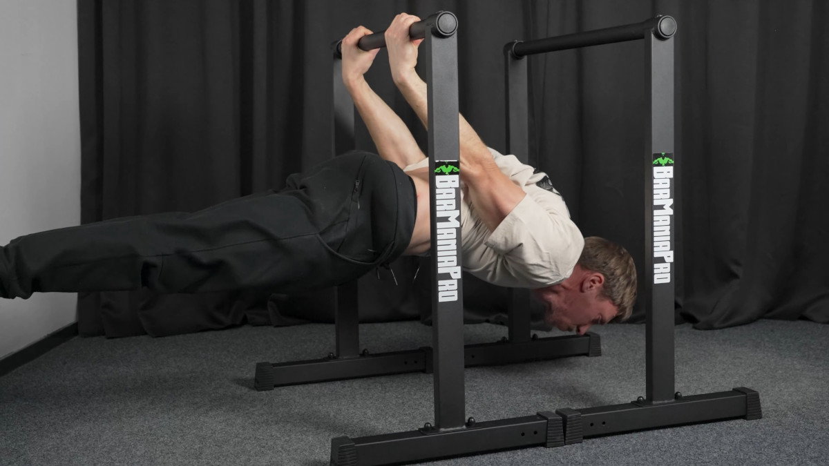 Man in white shirt performing a back lever on the barmania pro neo dip bars.