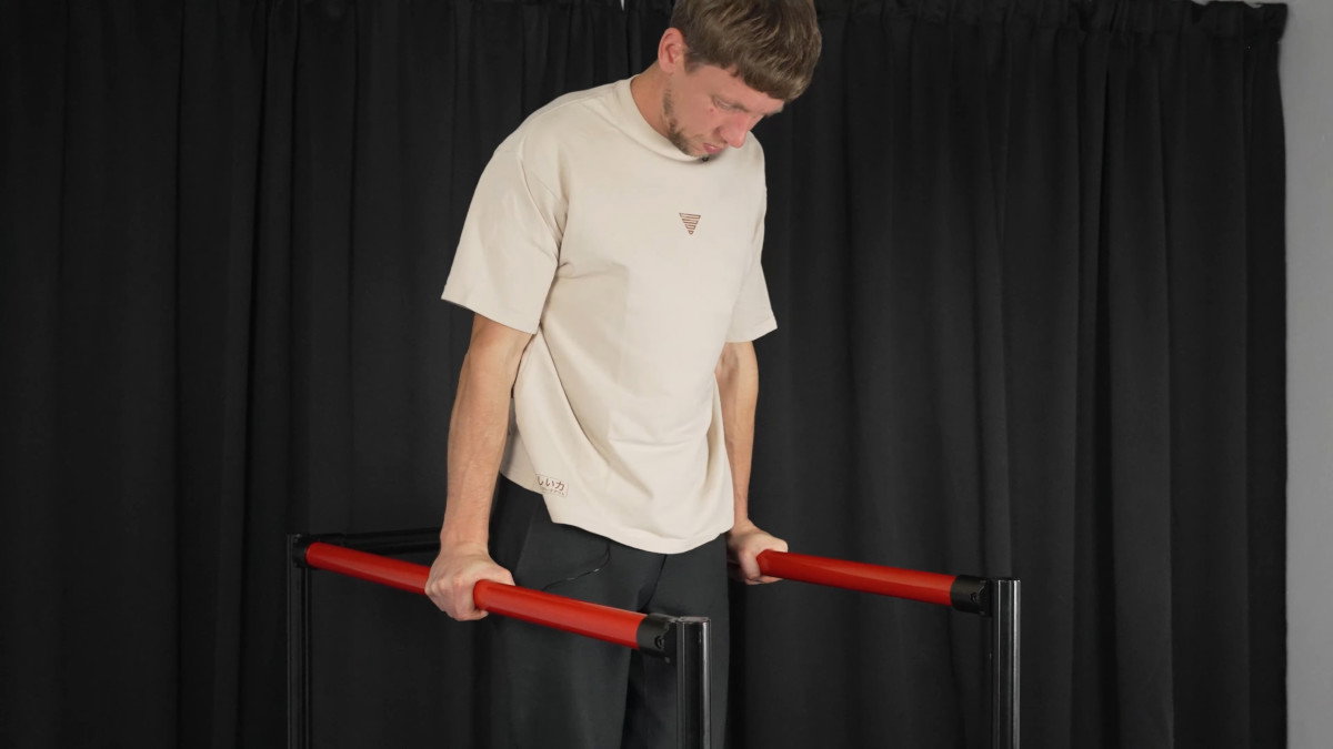 Man in white shirt performing dips on the fitnesskit dip bars.