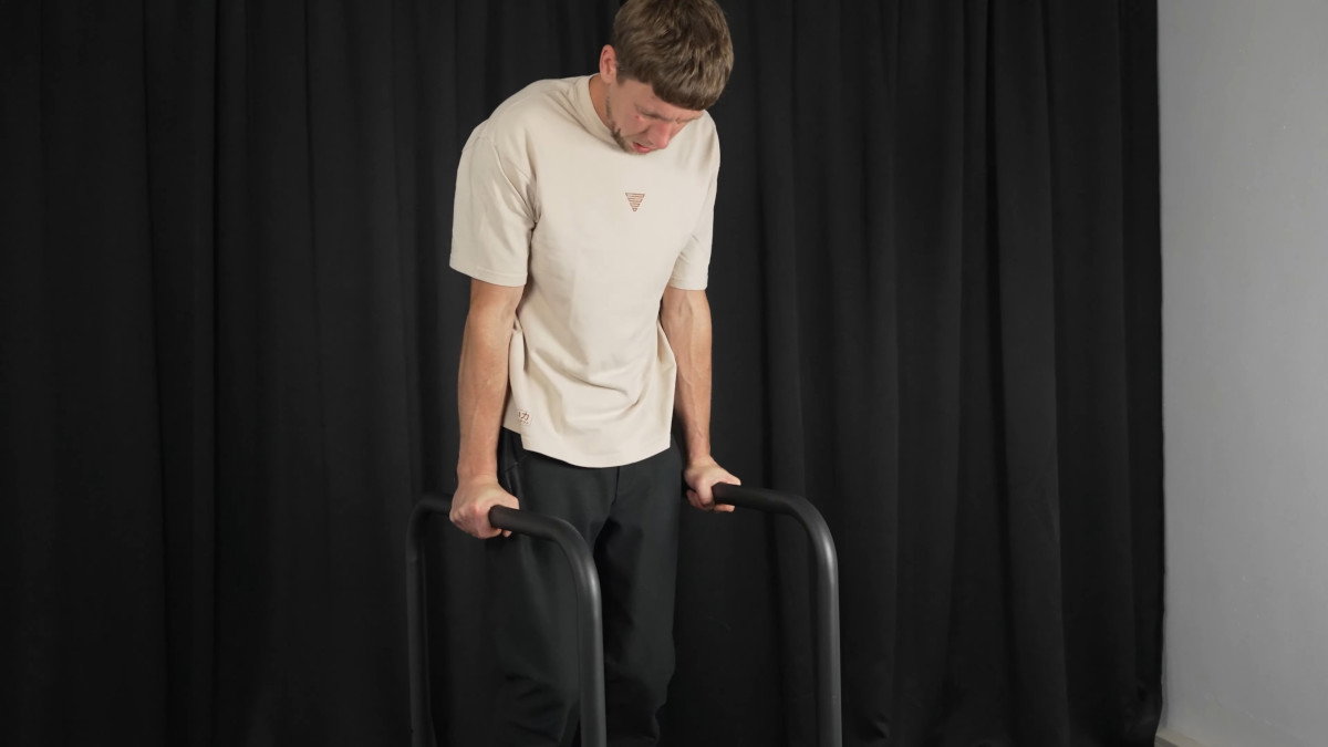 Man in white shirt performing dips on the gravity fitness dip bars.