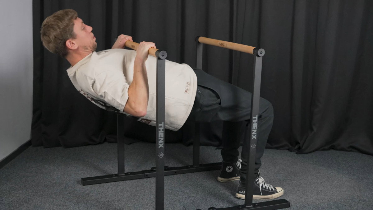 Man in white shirt performing rows on the thenx best dip bars.