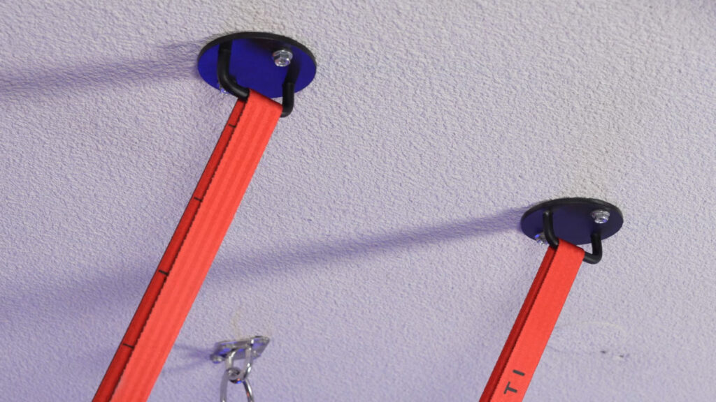 The MARMATI Ceiling Hooks fixed to a white ceiling with two taut orange straps suspended from them.