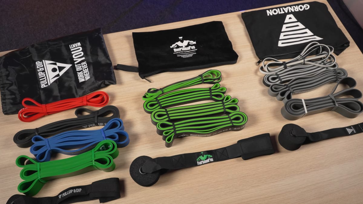 Three complete sets of resistance bands of varying weights, door anchors and carry bags from the brands gornation, barmania pro and pullup & dip.