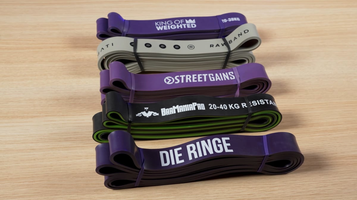Five medium-heavy resistance bands side by side from king of weighted, marmati, streetgains, barmania pro and die ringe.