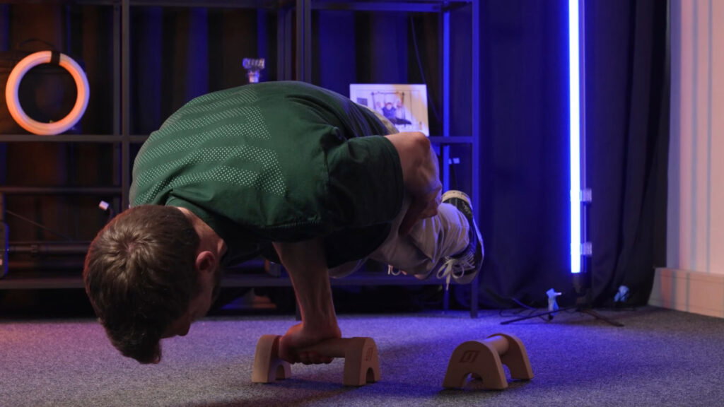 Man doing a one arm planche on gorletic parallettes as part of a compact home gym.