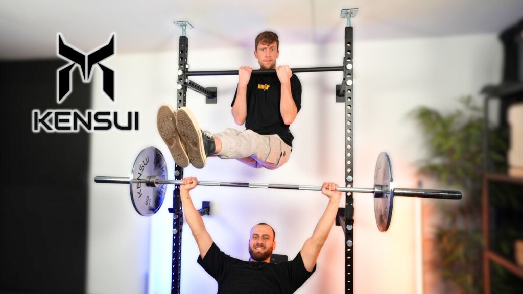 Two men making use of the Kensui Fitness Torii, one doing an L-sit on the top bar and the other doing bench presses.