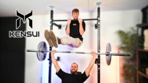 Two men making use of the Kensui Fitness Torii, one doing an L-sit on the top bar and the other doing bench presses.