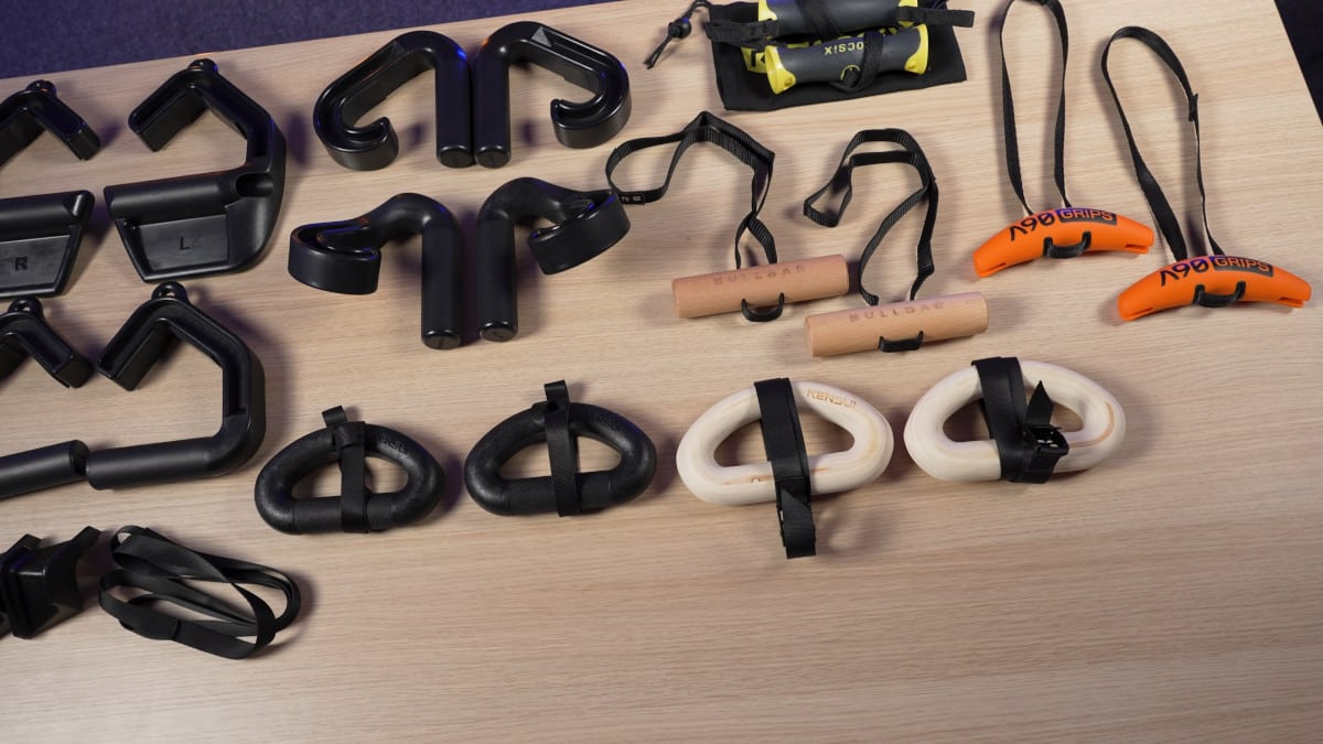 An assortment of pull-up handles from various brands displayed in a grid on a wooden table, including kensui and bullbar products.