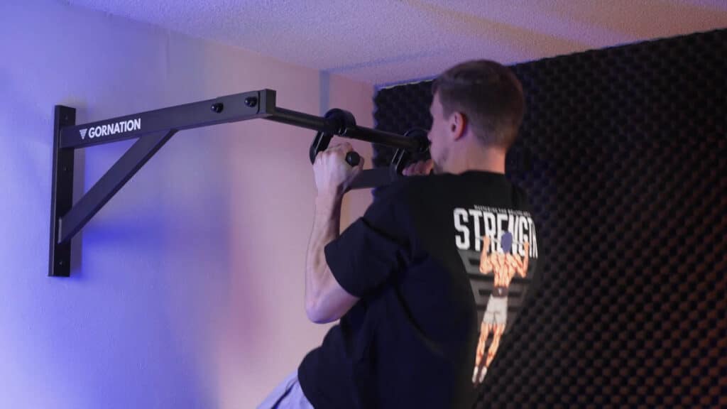 Man in black shirt doing neutral grip pull-ups with a pair of kensui swissies v1 hooked to a gornation ceiling pull-up bar.