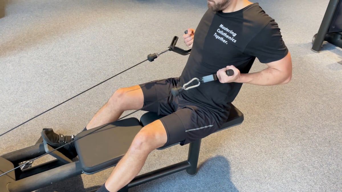 Man doing pull exercises on gym equipment, having swapped out the original handles for a set of kensui swissies v2 pull-up handles.