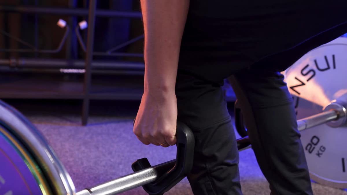 Man doing neutral grip dead lifts using the kensui swissies v2 clutching a barbell with heavy weight plates attached.