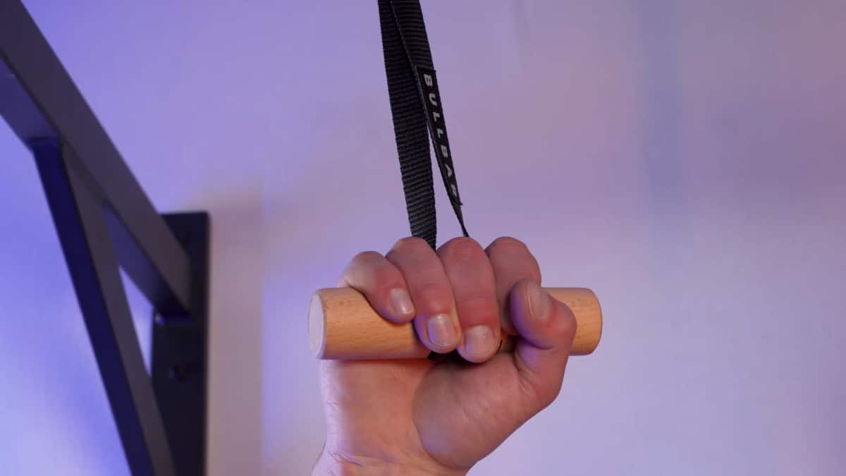 Close up of the bullbar pull-up handles showing its minimal design of a straight wooden handle with a strap pull through a hole in the center, a hand grasps the bar.