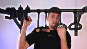 Man hanging on to various pull-up handles and looking questioningly at the camera.
