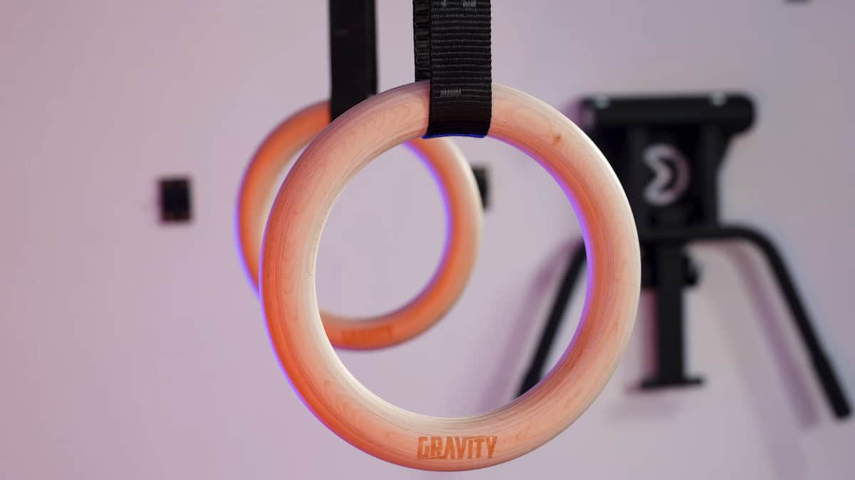 Detail of the gravity fitness gymnastic rings, showing the wood grain pattern and etched logo.
