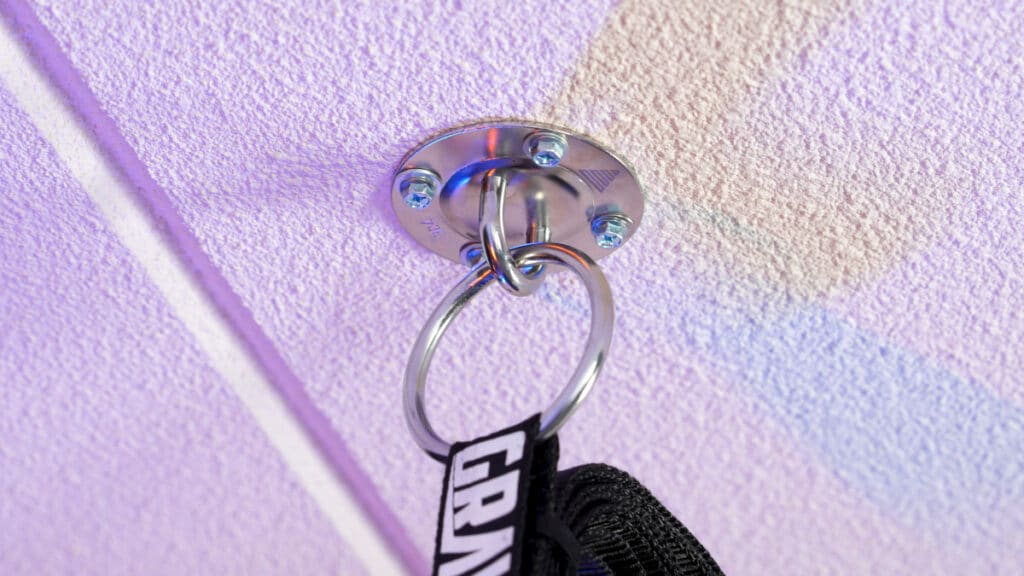 Gravity Fitness gymnastic rings suspended from die ringe ceiling hooks on a white ceiling.