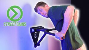 Man in green shirt doing dips on the streetgains wall-mounted dip bar while looking questioningly back over his shoulder at the viewer.