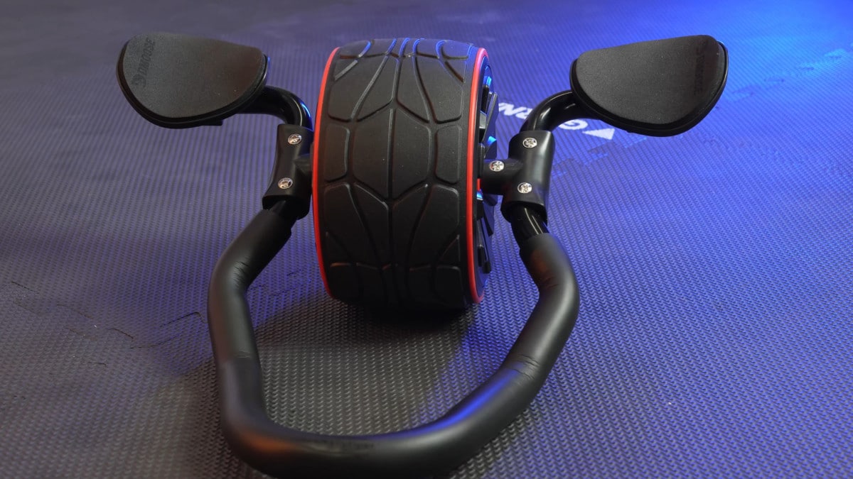 The dmoose ab roller resting on its brace on a gym mat floor.