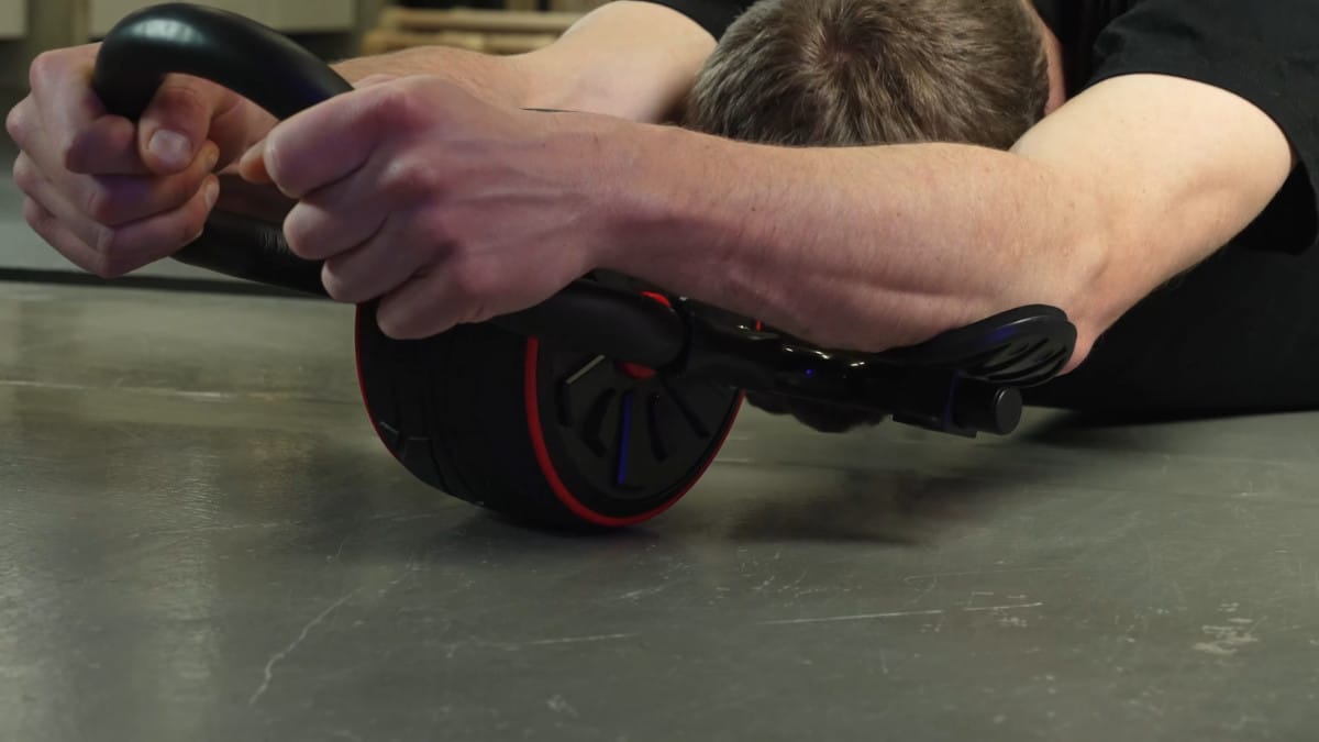 Man in black shirt completing a full ab rollout on the dmoose ab roller with his elbows resting on the elbow rests.