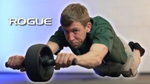 Man using the Rogue Ab Wheel to do ab roller roll outs while eyeballing the camera with a side eye.