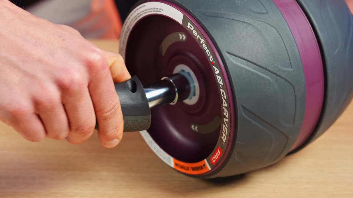 Man inserting one of the handles on the Perfect Fitness Ab Carver Pro into the wheel.