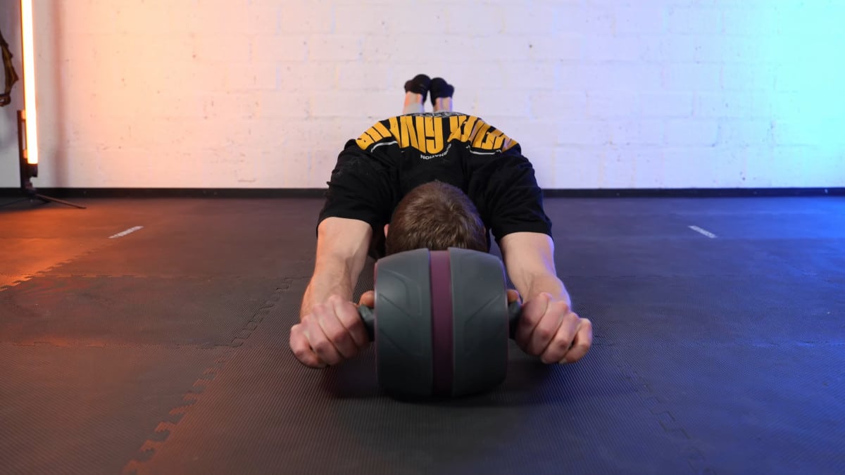Man in black shirt doing a full ab rollout on the Perfect Fitness Ab Carver Pro.