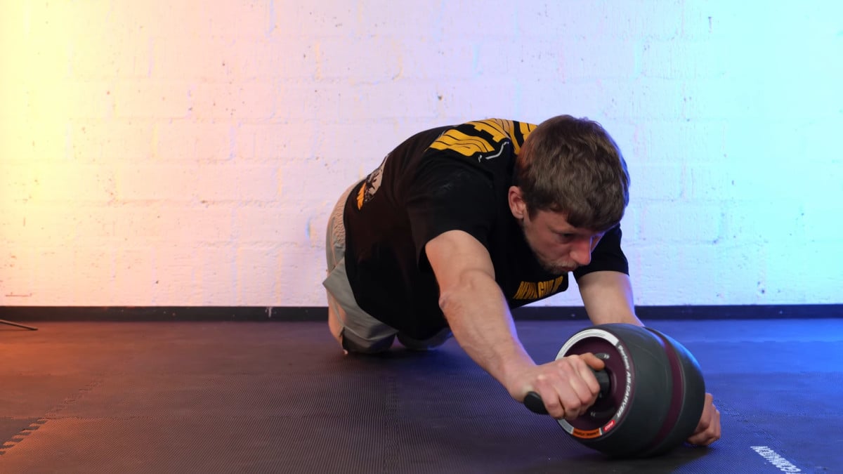 Man doing a ab rollout with the curve to his left on the Perfect Fitness Ab Carver Pro.