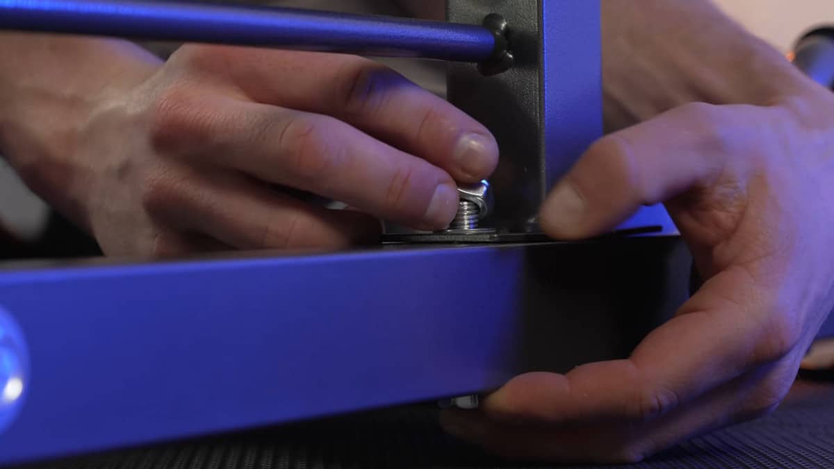 Man assembling the base of the relife power tower by applying a bolt and nut through the feet.