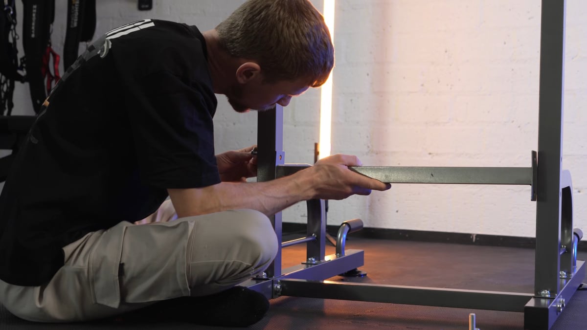 Man assembling the relife power tower by fastening a strut between the two vertical legs with nuts and bolts.