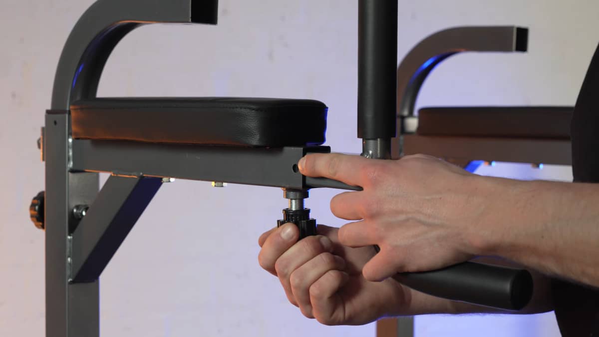 Man adjusting the length on the arm rests to the handles on the relife power tower by pulling down and turning the knob screw to release the handles in their sockets.