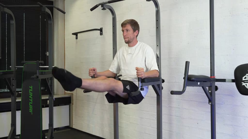 Man in white shirt doing leg raises on the relife power tower.
